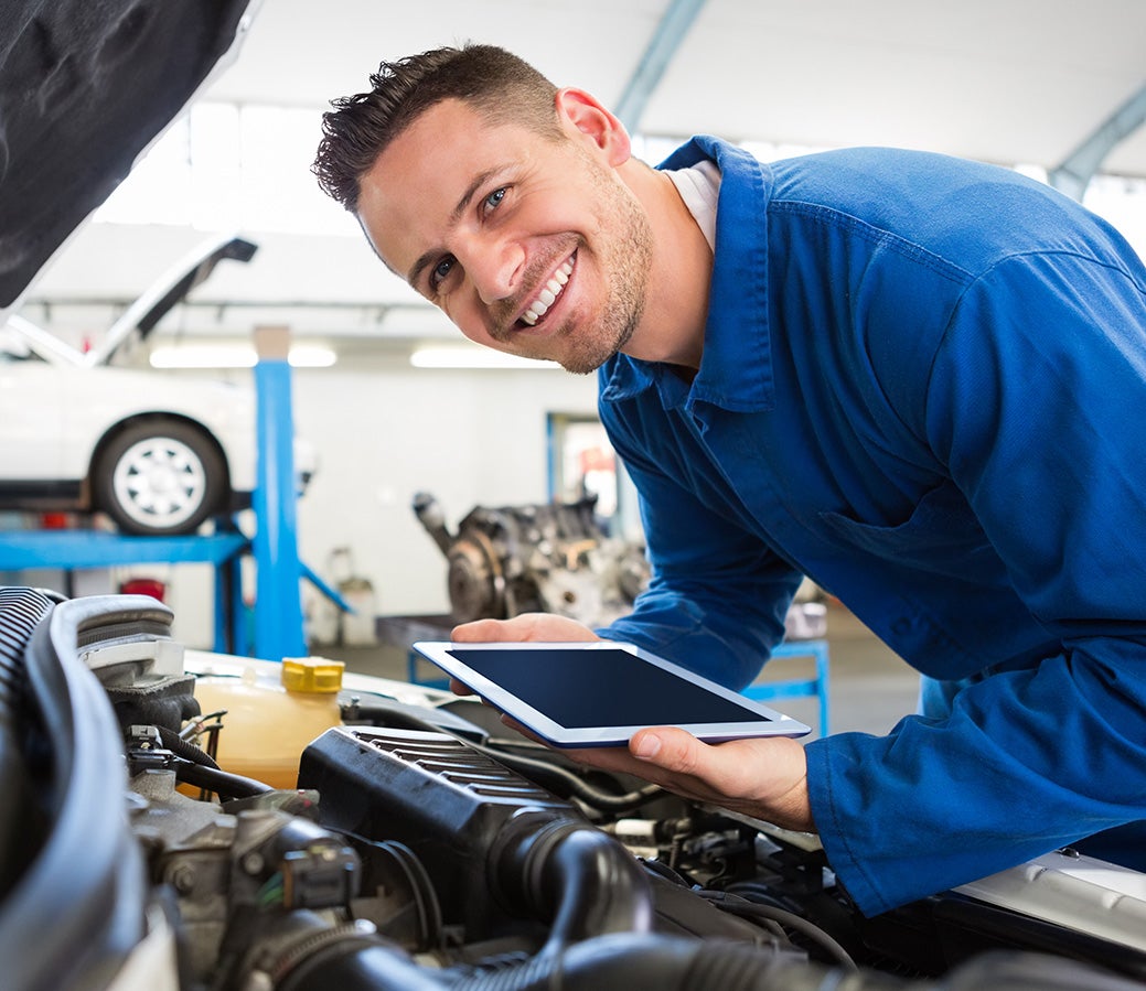 technician leaning over engine bay using tablet img